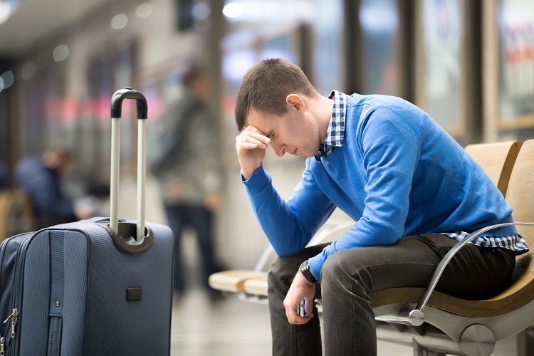 Passeggero in attesa all'aeroporto con la sua valigia.
