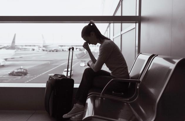 Immagine bianco e nero. Ragazza con valigia in attesa all'aeroporto.