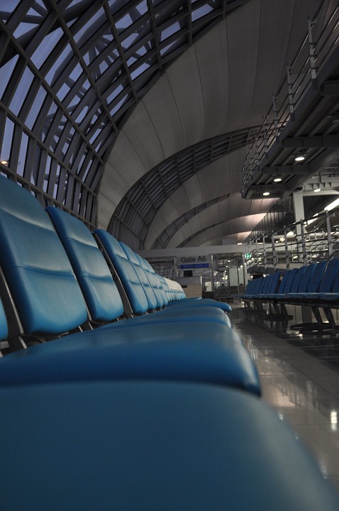 eine lange Reihe leerer Sitze an einem Flughafen, auf denen man sich zum schlafen hinlegen kann