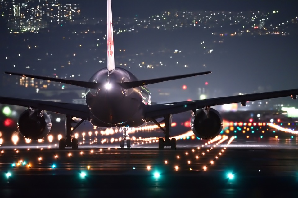 Ein Flugzeug landet auf beleuchteter Landebahn
