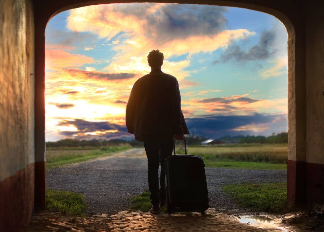 homme regardant l'horizon avec une valise à la main